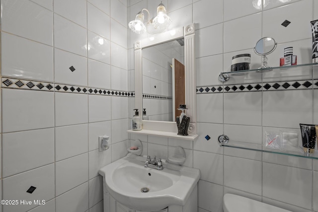 half bathroom featuring toilet, a sink, and tile walls