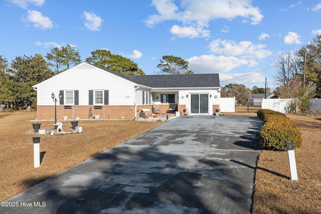 ranch-style house with driveway, brick siding, and fence