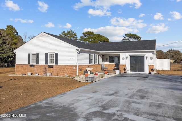 ranch-style home featuring driveway, brick siding, and fence