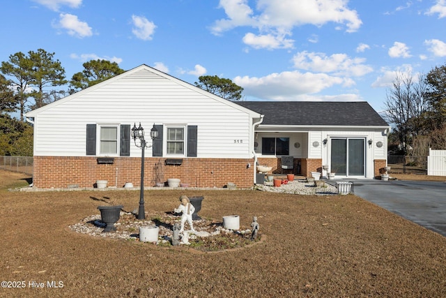 ranch-style home featuring concrete driveway, brick siding, fence, and a front lawn