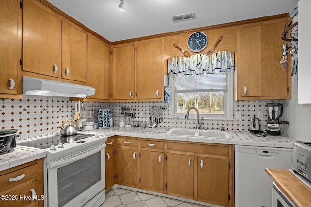 kitchen featuring tasteful backsplash, visible vents, a sink, white appliances, and under cabinet range hood