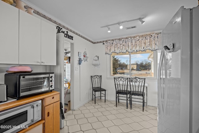 kitchen featuring a toaster, visible vents, white cabinets, stainless steel microwave, and ornamental molding