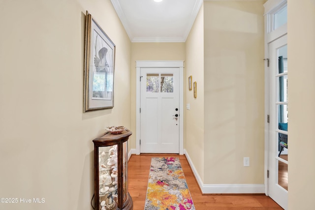 doorway to outside with ornamental molding, light wood-type flooring, and baseboards