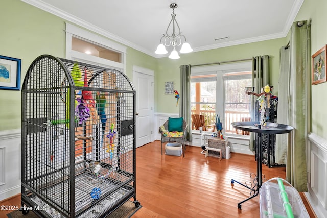 interior space with ornamental molding, wood finished floors, and an inviting chandelier