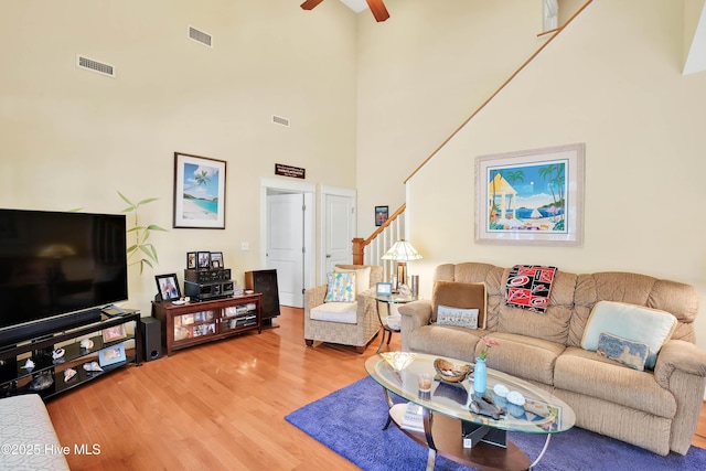 living area featuring light wood finished floors, stairway, visible vents, and a ceiling fan