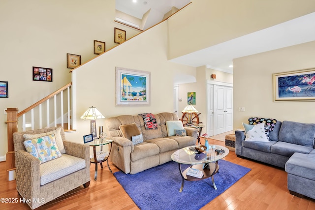 living area featuring stairs, wood finished floors, and a towering ceiling