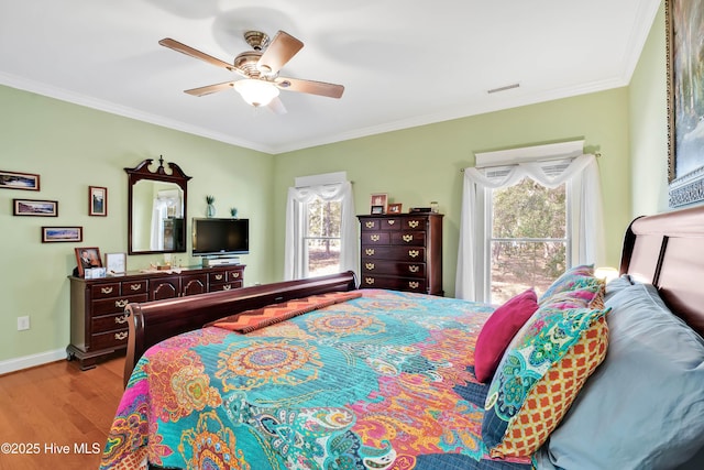 bedroom featuring visible vents, baseboards, a ceiling fan, wood finished floors, and crown molding