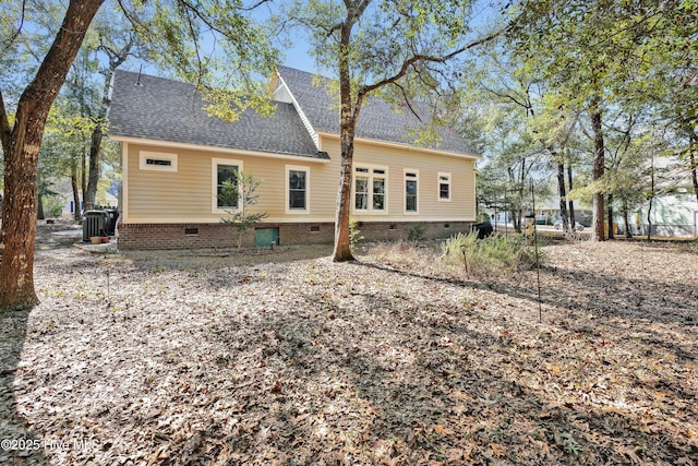 rear view of property featuring crawl space, a shingled roof, and central AC