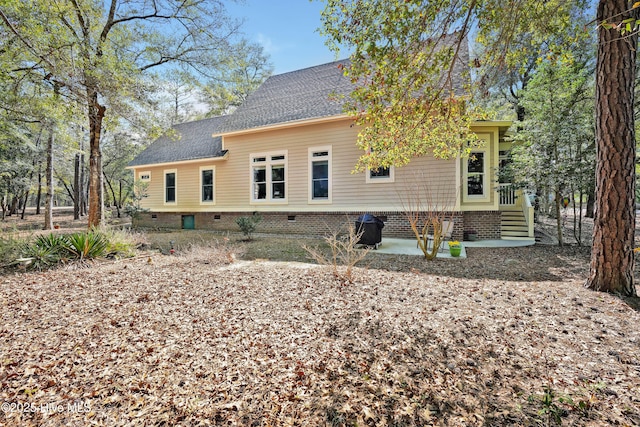 back of house featuring entry steps and roof with shingles