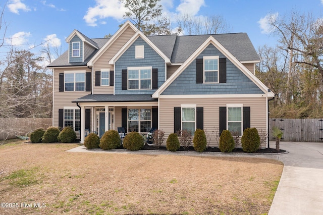 view of front facade with covered porch, fence, and a front lawn