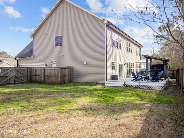 back of house with a fenced backyard, a yard, and a deck