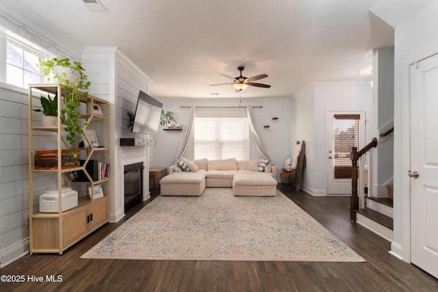 living room featuring a large fireplace, stairs, a wealth of natural light, and dark wood-type flooring