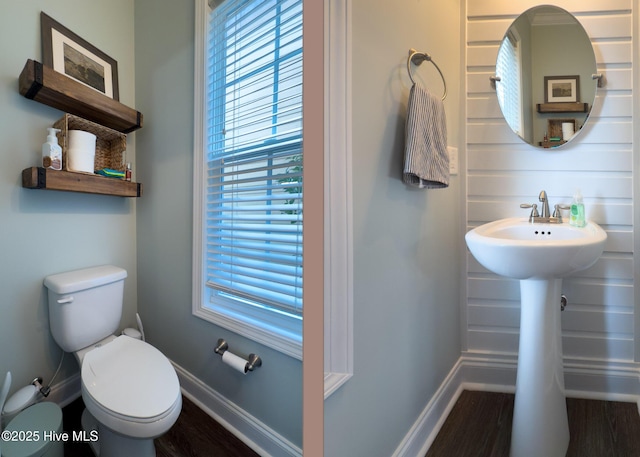 half bathroom with baseboards, toilet, and wood finished floors