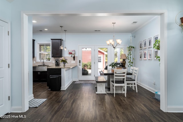 dining area with dark wood-style floors, baseboards, ornamental molding, and a notable chandelier