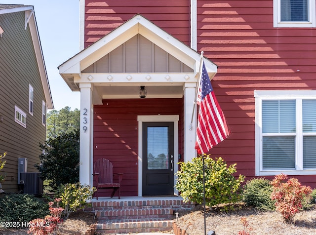 doorway to property with board and batten siding, covered porch, and central air condition unit