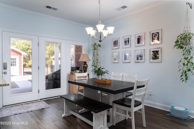 dining space featuring dark wood-type flooring, a chandelier, visible vents, and ornamental molding