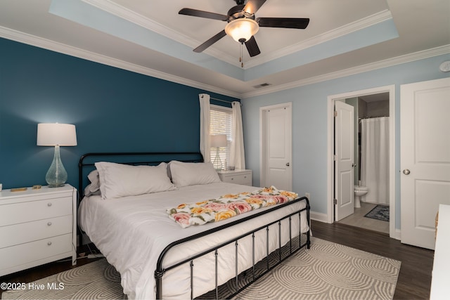 bedroom featuring visible vents, a tray ceiling, wood finished floors, and ornamental molding