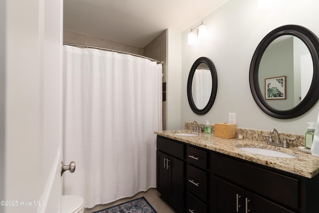 full bathroom featuring curtained shower, a sink, toilet, and double vanity