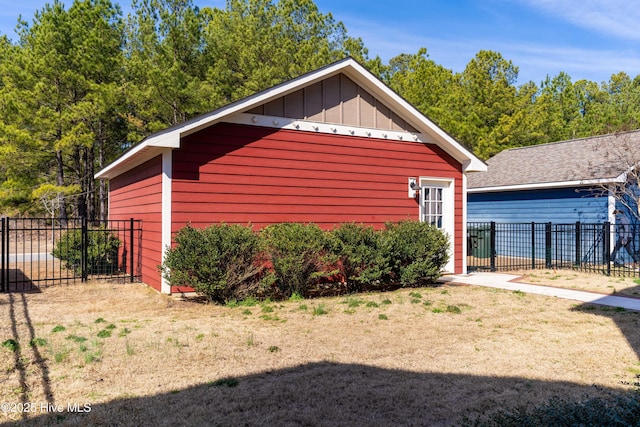 view of side of property featuring board and batten siding, fence, and a lawn