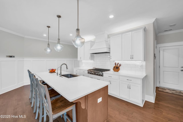 1066 Bradshaw Ter, Wilmington, NC 28412 - kitchen featuring a sink, a kitchen island with sink, custom range hood, ornamental molding, and stainless steel gas cooktop