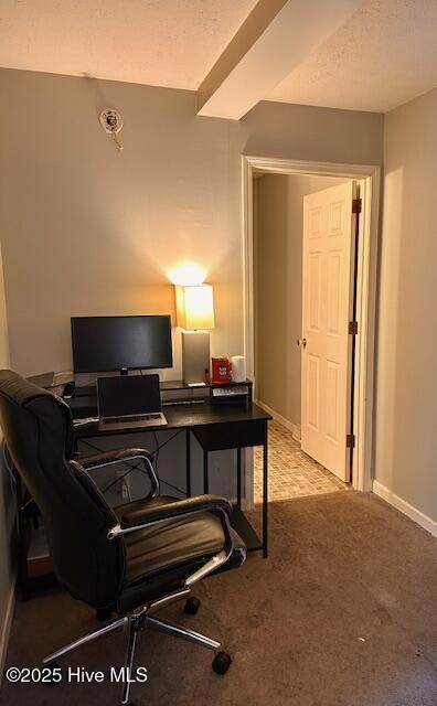 home office with baseboards, a textured ceiling, and light colored carpet