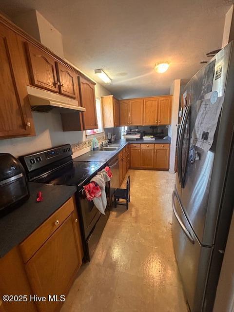 kitchen featuring brown cabinets, freestanding refrigerator, a sink, under cabinet range hood, and black / electric stove