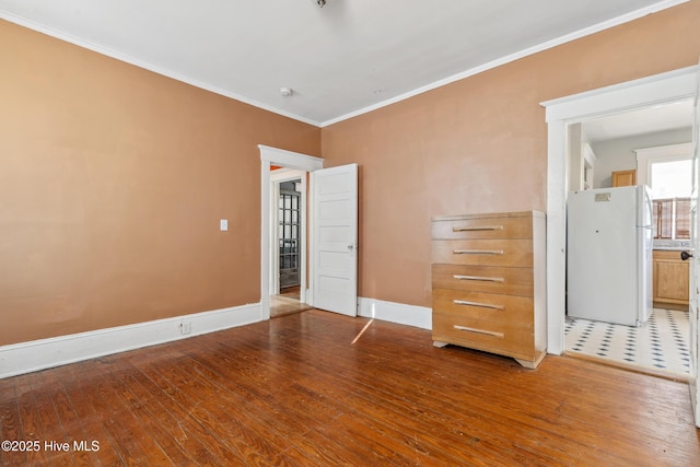 unfurnished bedroom with ornamental molding, wood-type flooring, freestanding refrigerator, and baseboards