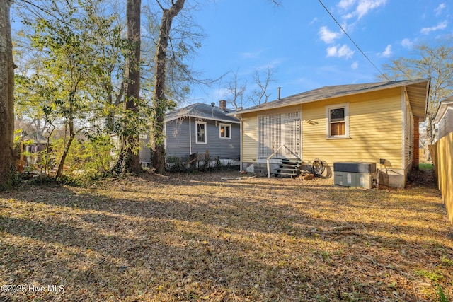 rear view of property featuring entry steps, central AC, and fence