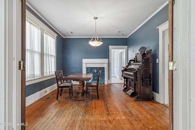 dining area with ornamental molding, wood finished floors, visible vents, and baseboards