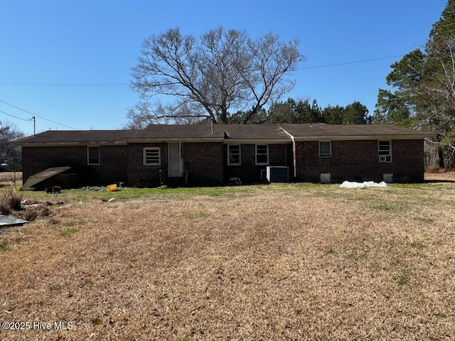 view of front of home featuring a front yard, brick siding, and central AC unit