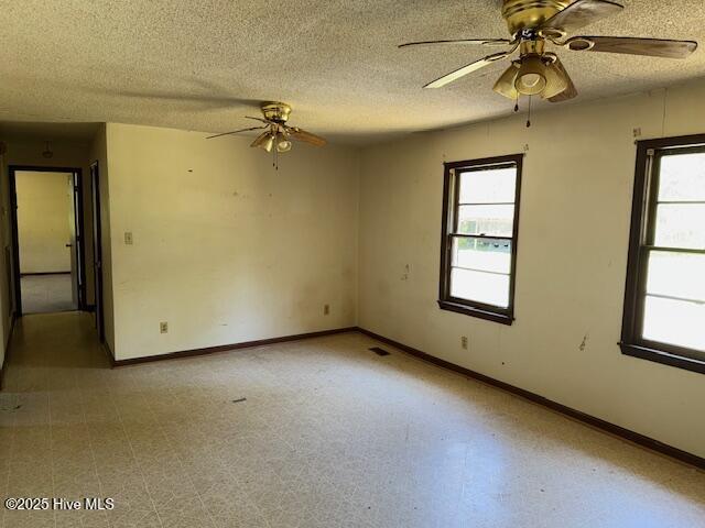 350 Randolphville Rd NE, Bolivia, NC 28422 - empty room with baseboards, a ceiling fan, a textured ceiling, and a wealth of natural light