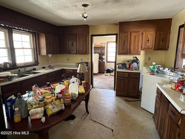 kitchen with a textured ceiling, light countertops, separate washer and dryer, and a sink