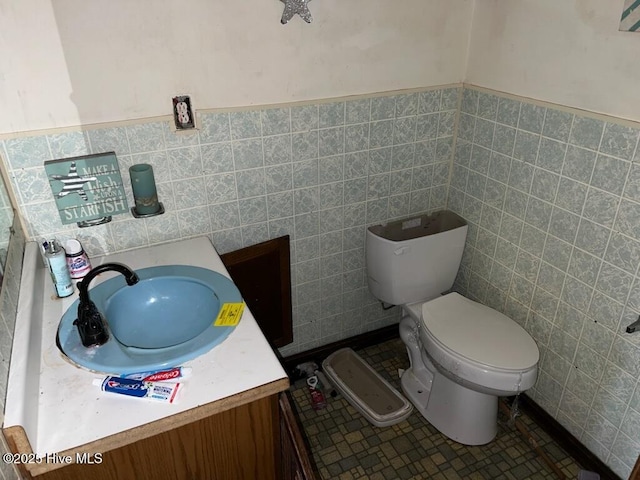 half bath with tile patterned floors, vanity, toilet, and tile walls