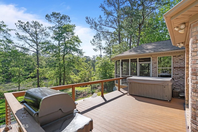 wooden deck with a hot tub, grilling area, and a sunroom