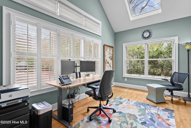 office space with a skylight, high vaulted ceiling, baseboards, and wood finished floors