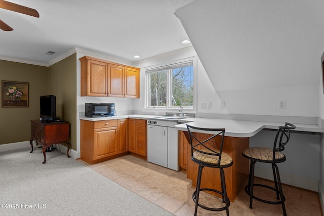 kitchen with ceiling fan, black microwave, light countertops, a peninsula, and ornamental molding