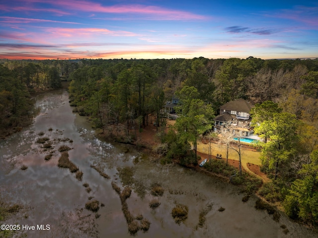 aerial view at dusk featuring a view of trees
