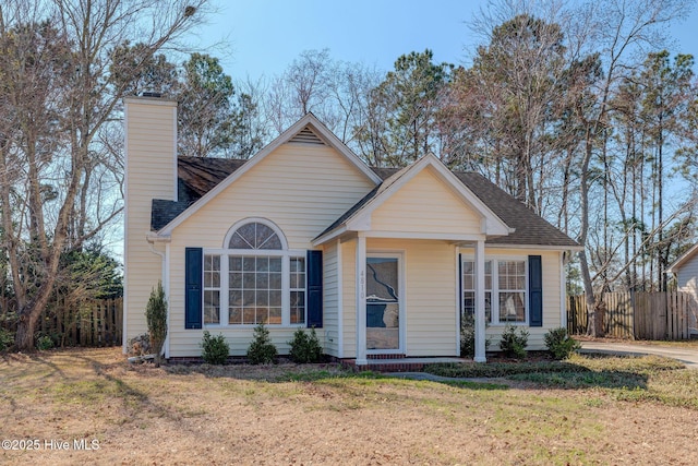 view of front facade featuring a shingled roof, fence, a chimney, and a front lawn