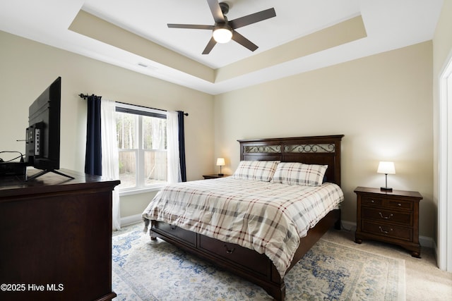 carpeted bedroom with a tray ceiling, baseboards, and visible vents