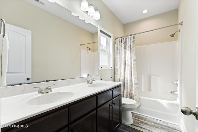 full bath featuring visible vents, shower / bath combination with curtain, toilet, and a sink