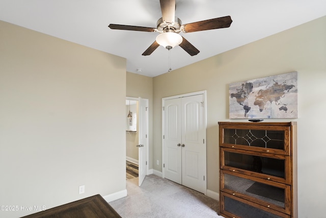 bedroom with a ceiling fan, light colored carpet, a closet, and baseboards