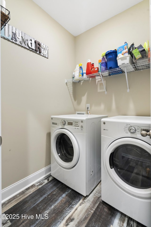 clothes washing area featuring laundry area, baseboards, dark wood-type flooring, and washing machine and clothes dryer