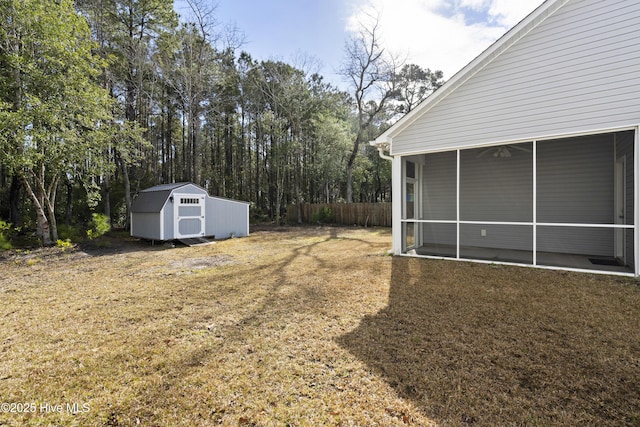 view of yard featuring an outbuilding, a storage unit, a sunroom, and fence