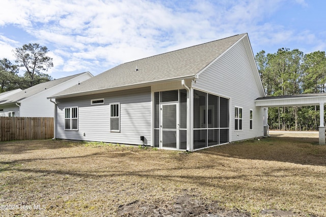 back of house featuring a yard, fence, a shingled roof, and a sunroom