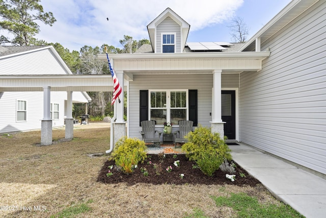 entrance to property featuring covered porch and roof mounted solar panels