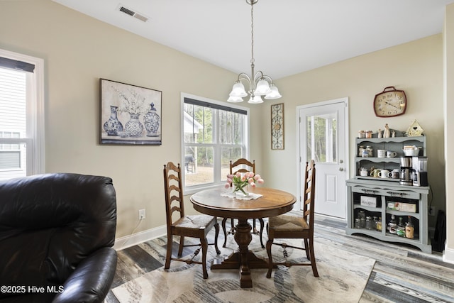 dining area with visible vents, baseboards, wood finished floors, and a chandelier