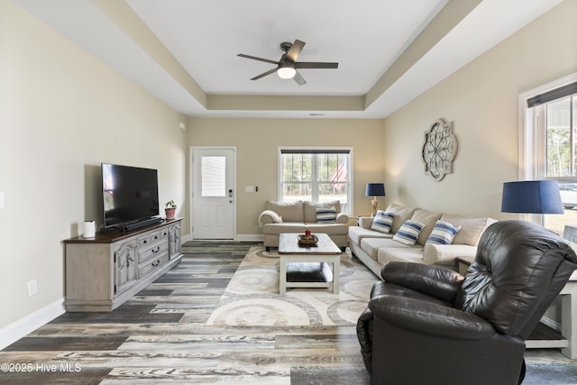 living room with plenty of natural light, a raised ceiling, and baseboards