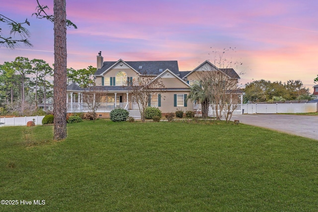 view of front of property featuring a lawn, covered porch, a chimney, and fence