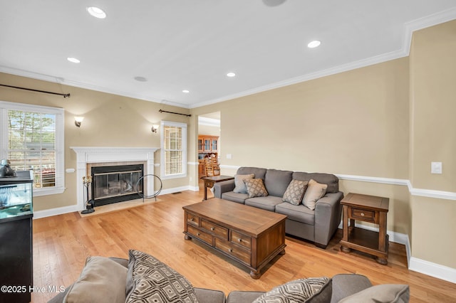 living area featuring baseboards, a fireplace with flush hearth, recessed lighting, ornamental molding, and light wood-type flooring