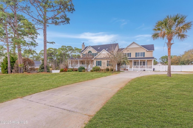 view of front facade with driveway, a porch, a front yard, and fence